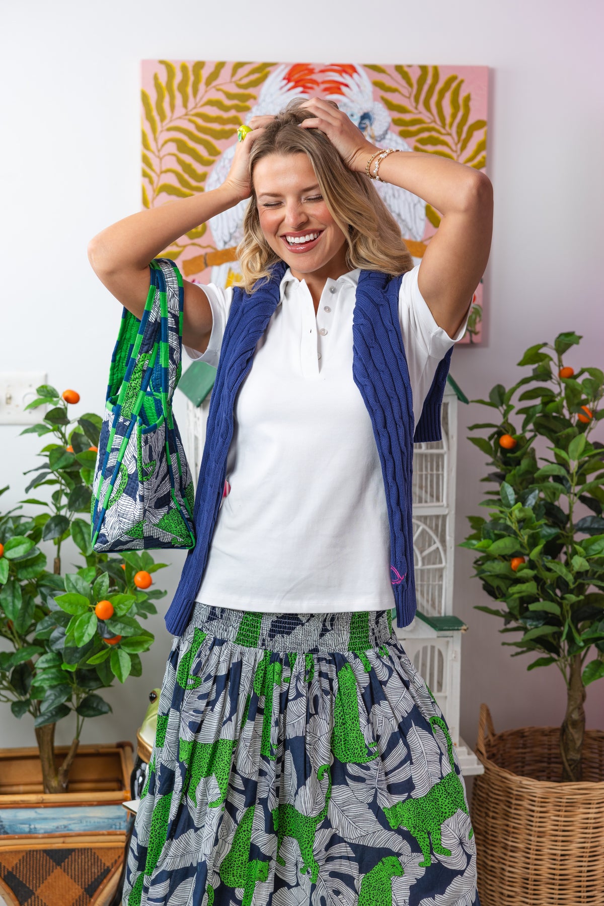 Woman in a colorful outfit standing in a room with plants and a painting.